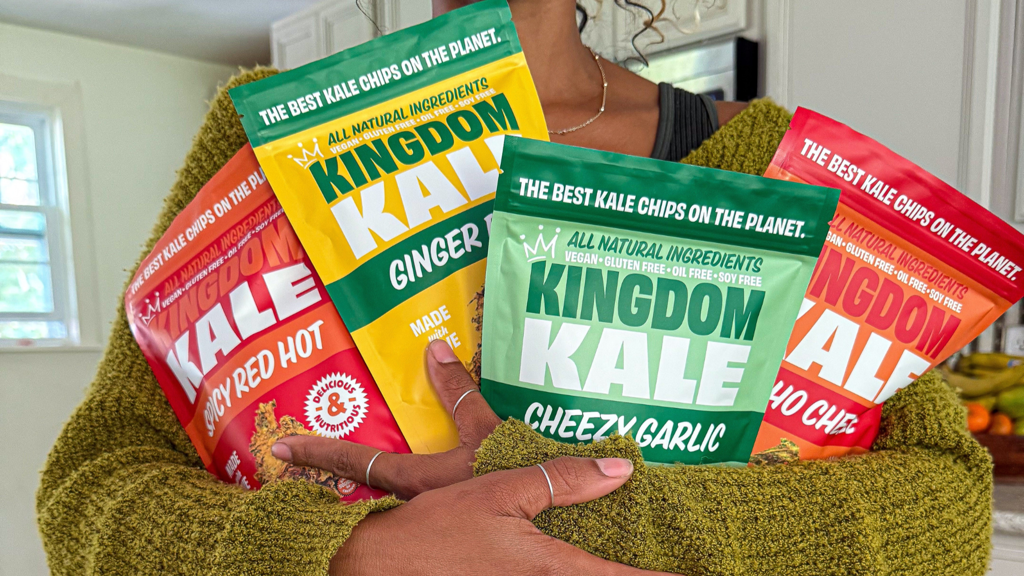 Person holding Kingdom Kale chips in a kitchen setting